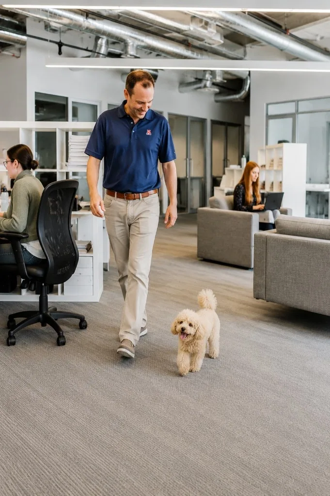 Man walking a poodle through an open-plan office