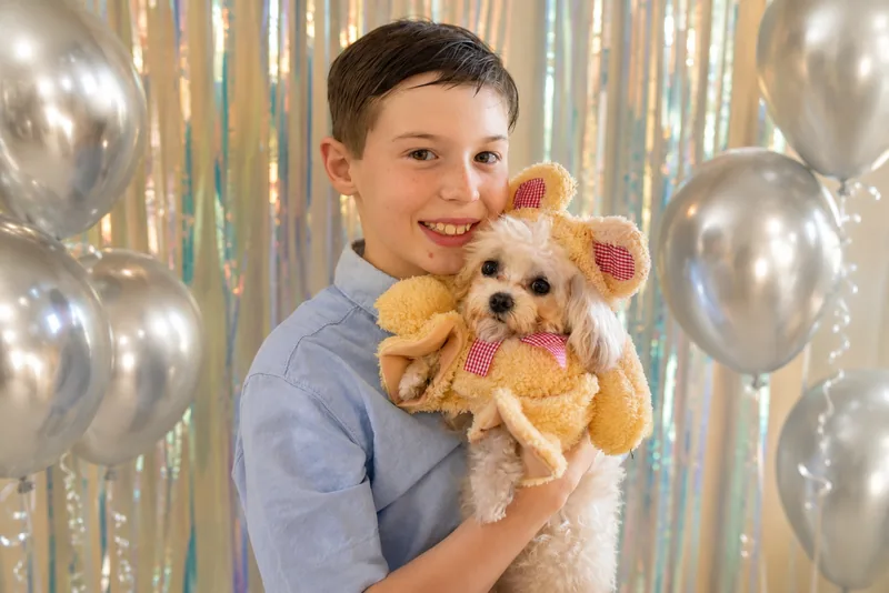 Boy with a poodle in front of a balloon backdrop