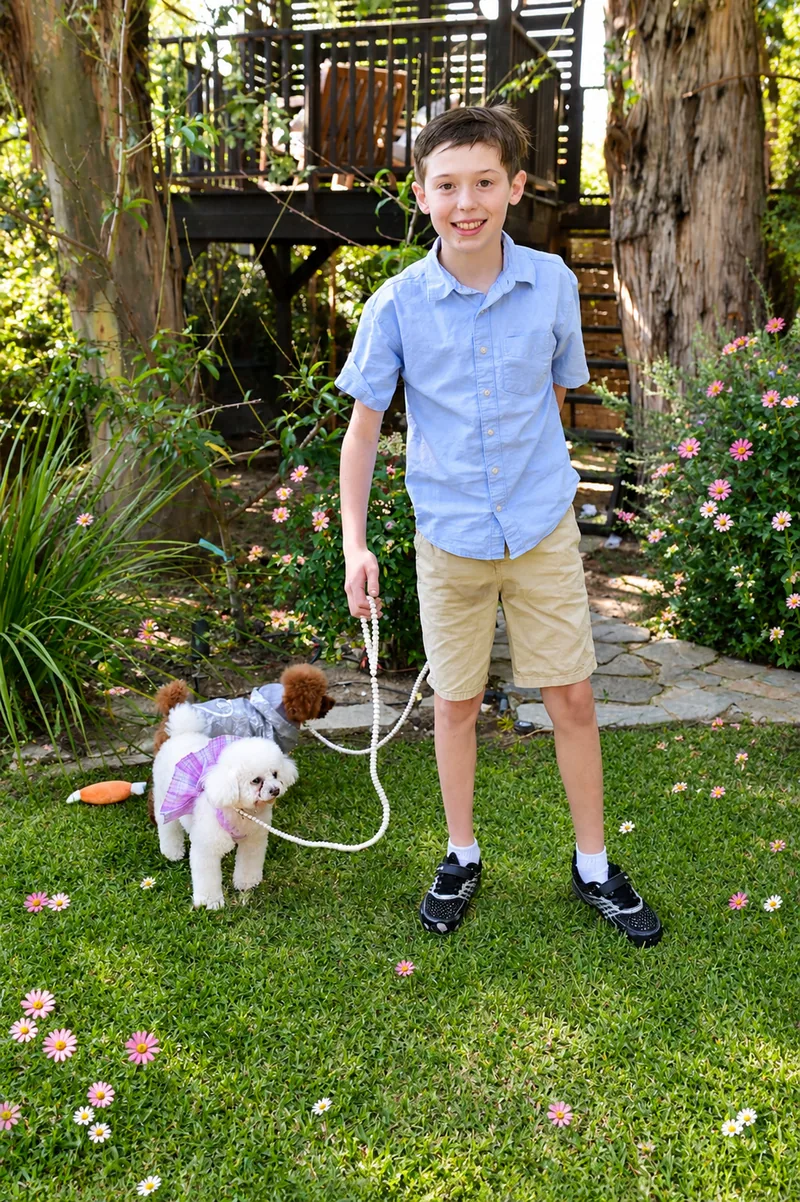 Boy walking a teacup poodle on a lawn at a birthday party